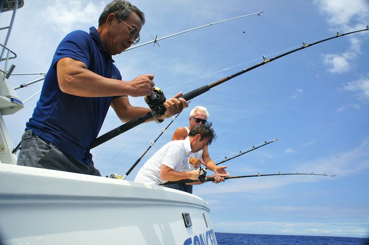 Three men are fishing on a boat in the ocean.