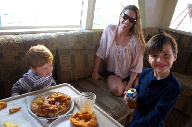 A woman and two children are sitting at a table with food.