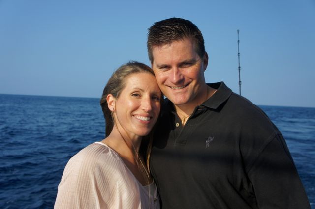 A man and a woman are posing for a picture in front of the ocean