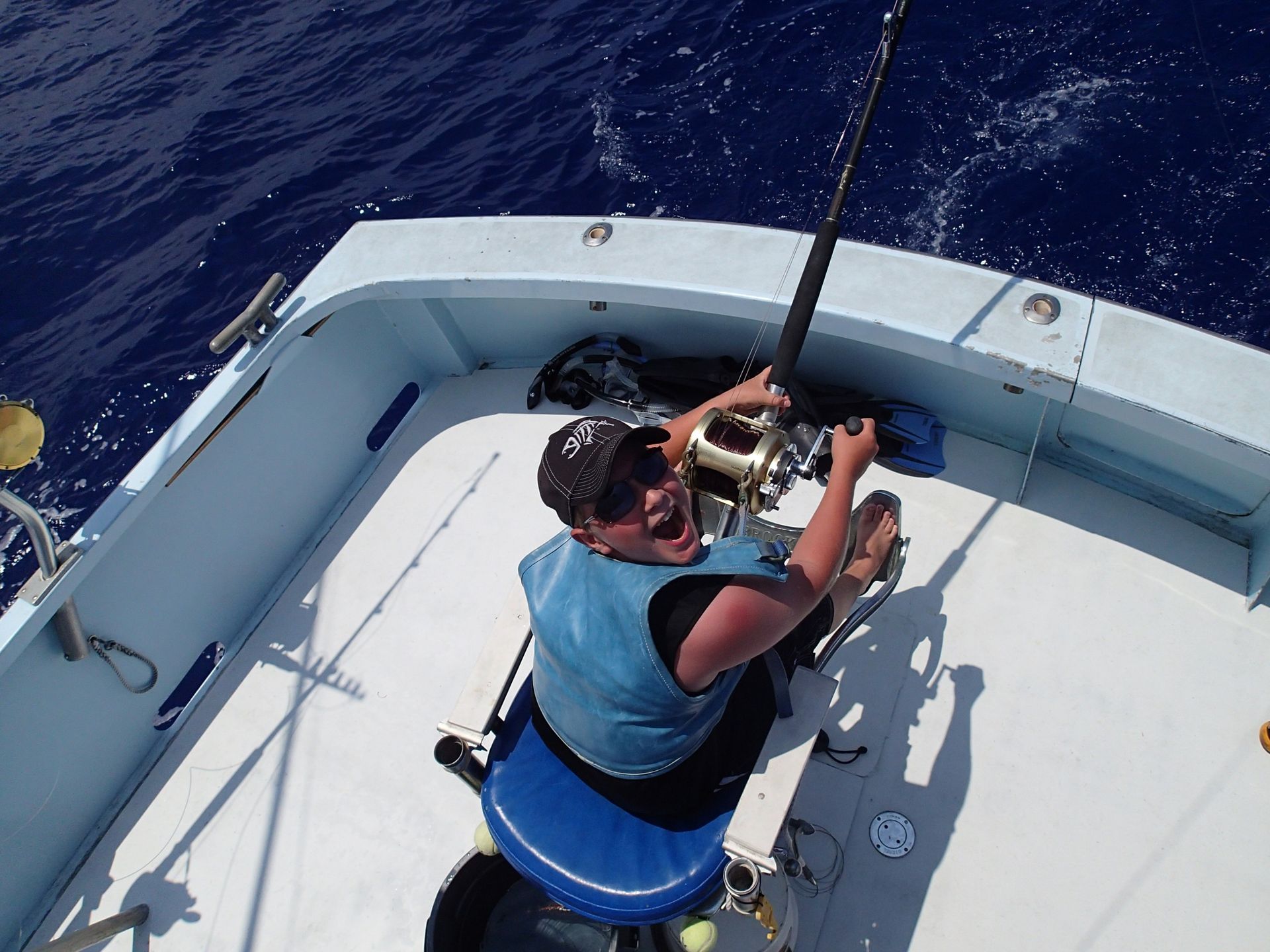 A man is sitting on a boat holding a fishing rod