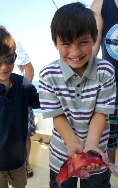 A boy in a striped shirt is holding a fish