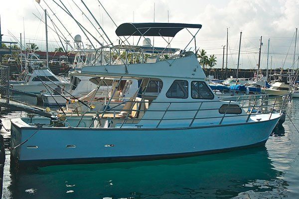 A large white boat is docked in a marina.