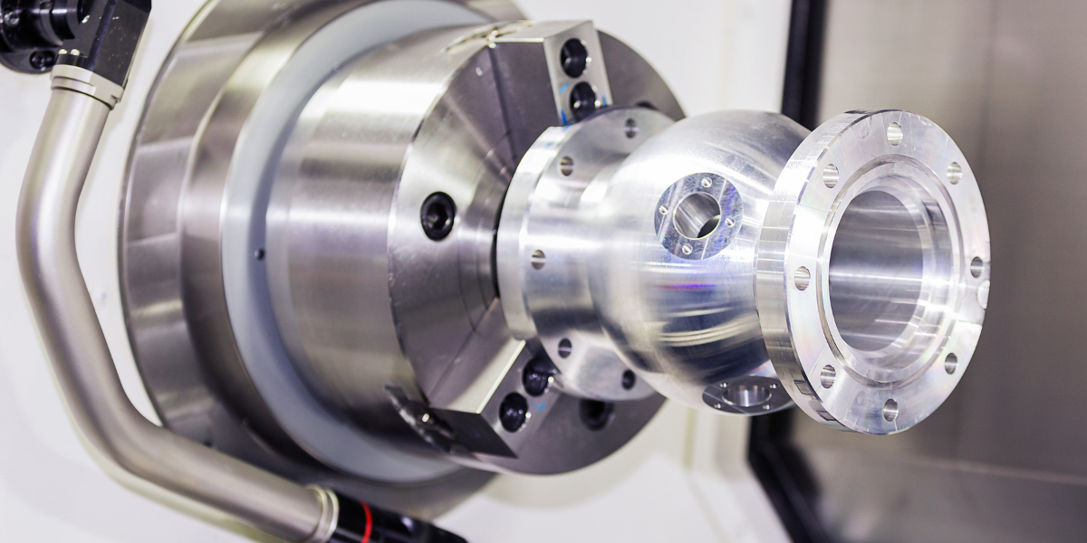 A metal sphere component is clamped in a machine chuck, ready for machining.