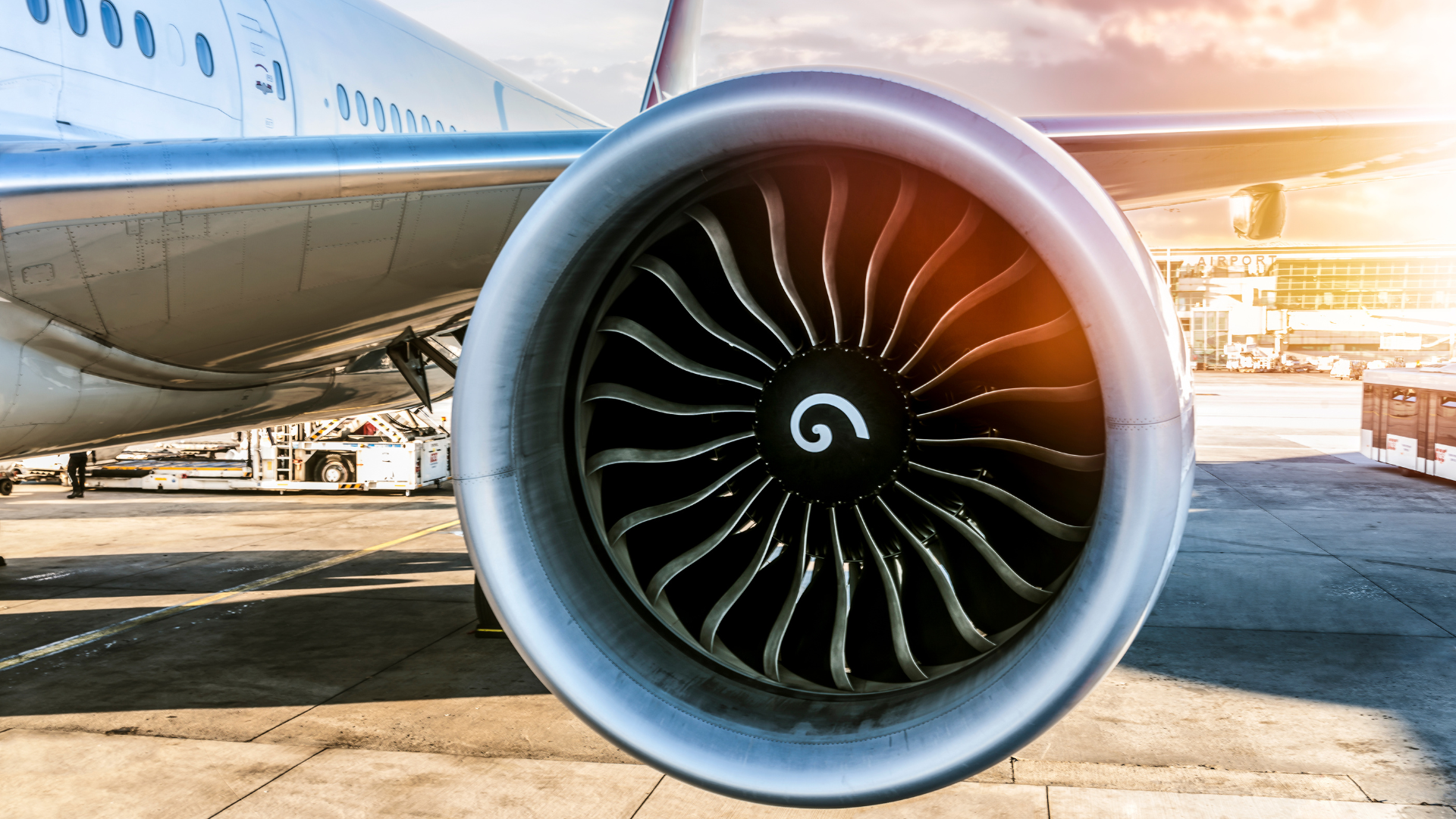Jet engine of a passenger airplane on the tarmac with a sunlit background.