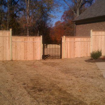 A wooden fence with a gate in front of a house.