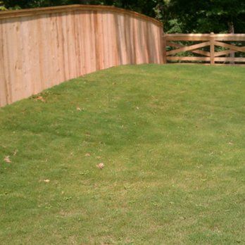 A wooden fence surrounds a lush green field of grass.