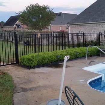 A black fence surrounds a swimming pool in a backyard.