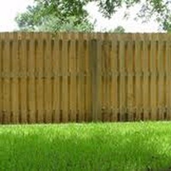 A wooden fence surrounds a lush green lawn.