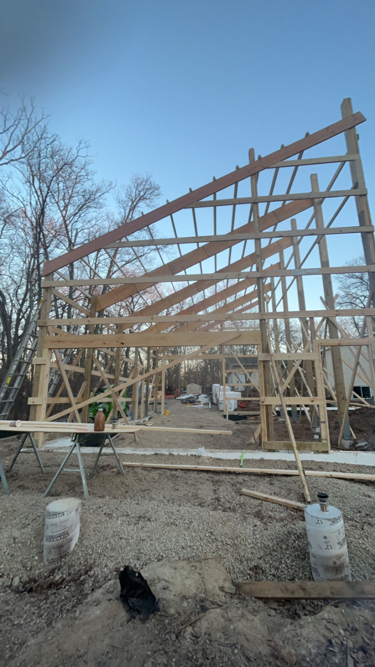 Interior framing of a room under construction; exposed studs, pipes, and wiring; light wood and gray cement.