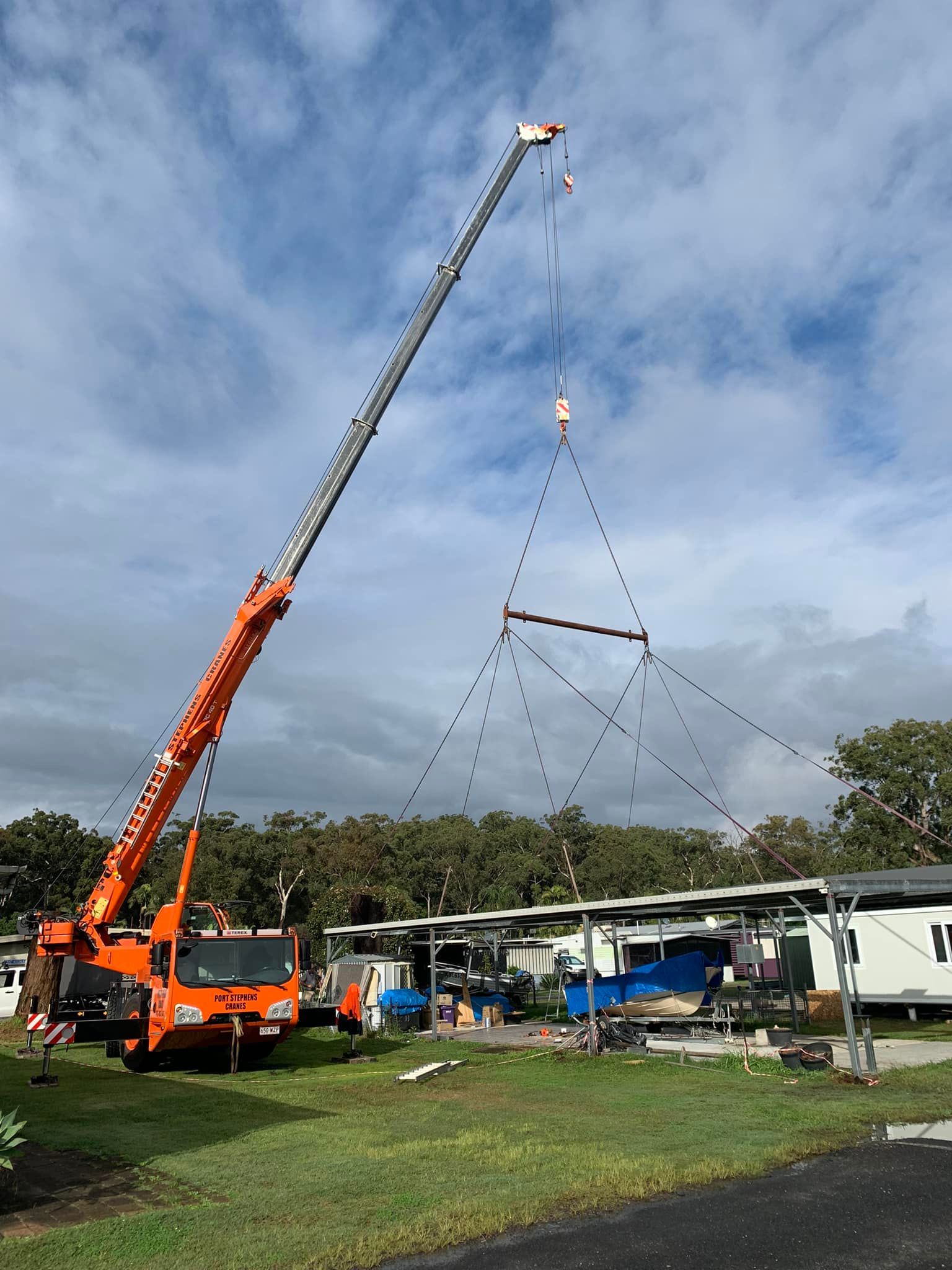 A Red Aerial Lift Is Parked On The Side Of The Road Next To An Orange Cone — Port Stephens Cranes In Hunter Valley, NSW
