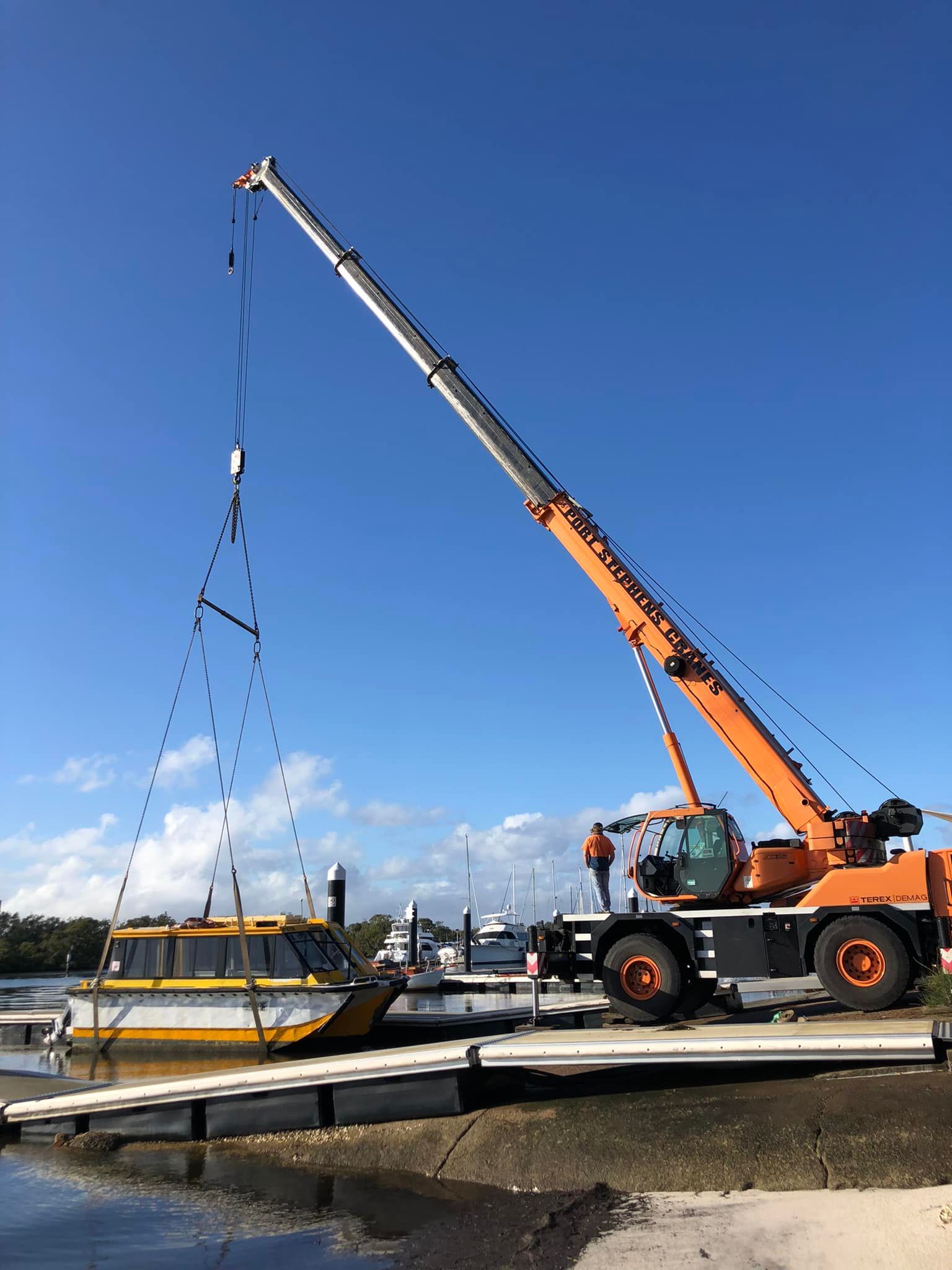 A Yellow Excavator Is Loading Metal Into A Pile Of Scrap Metal — Port Stephens Cranes In Maitland, NSW