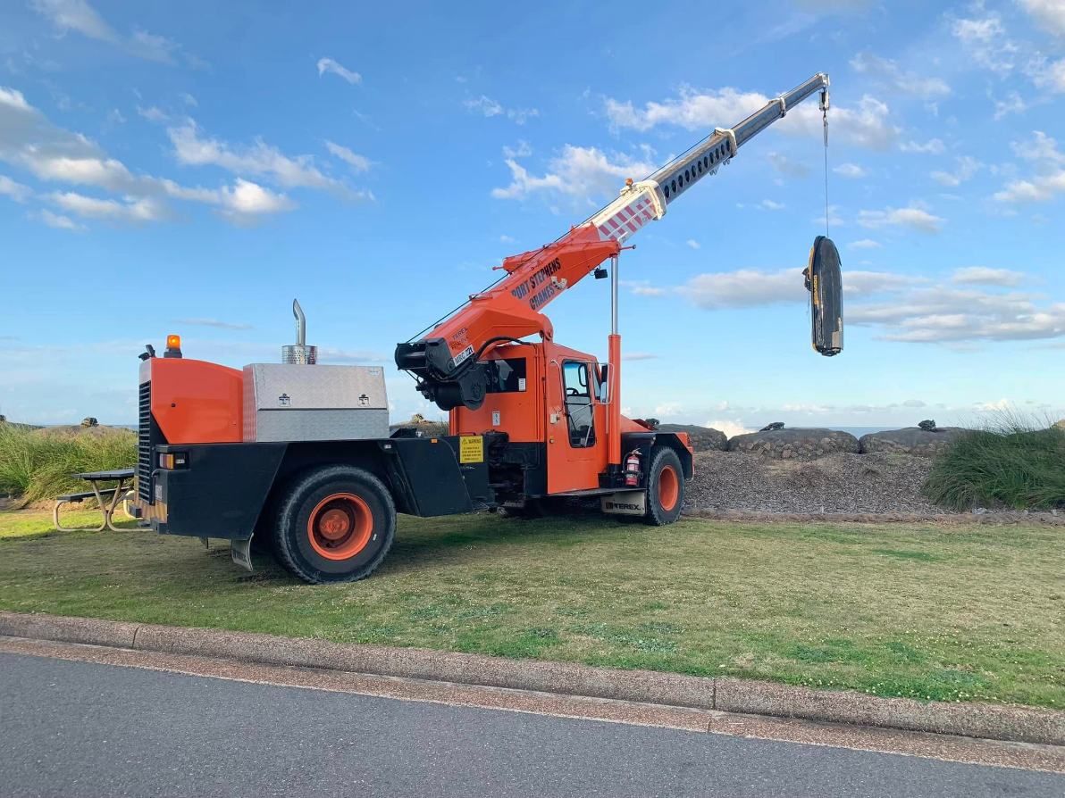 An Orange Truck With A Crane Attached To It Is Parked On The Side Of The Road — Port Stephens Cranes In Salt Ash, NSW