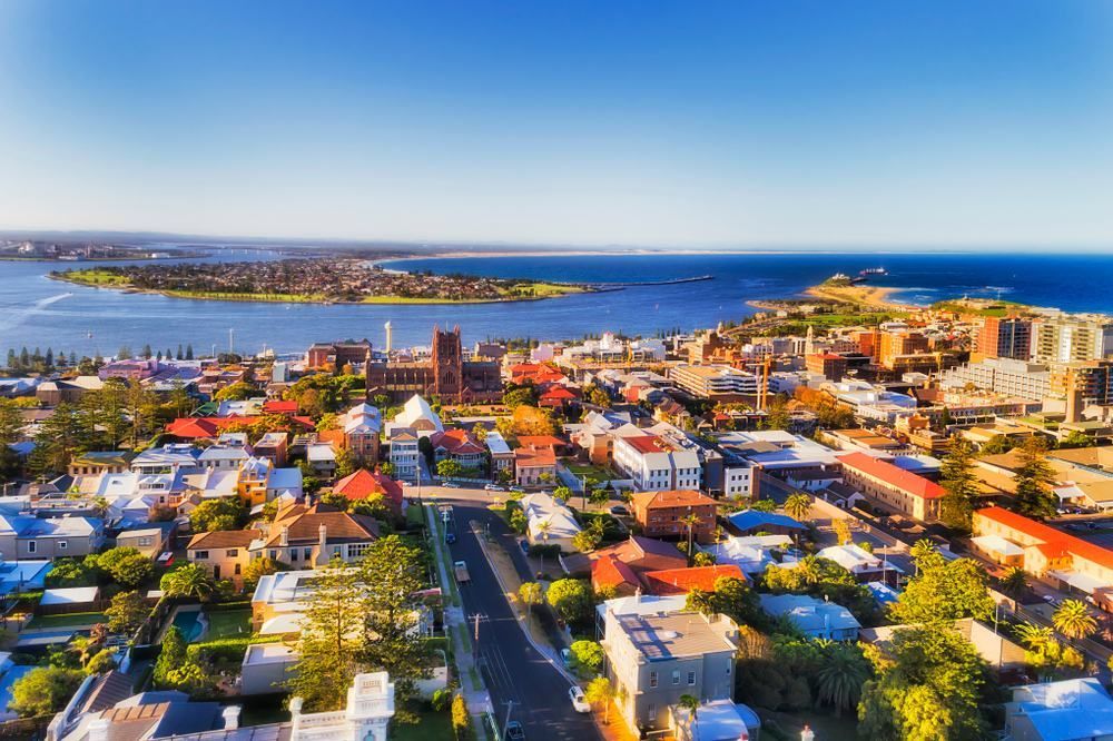 An Aerial View Of A City With A Body Of Water In The Background — Port Stephens Cranes In Newcastle, NSW