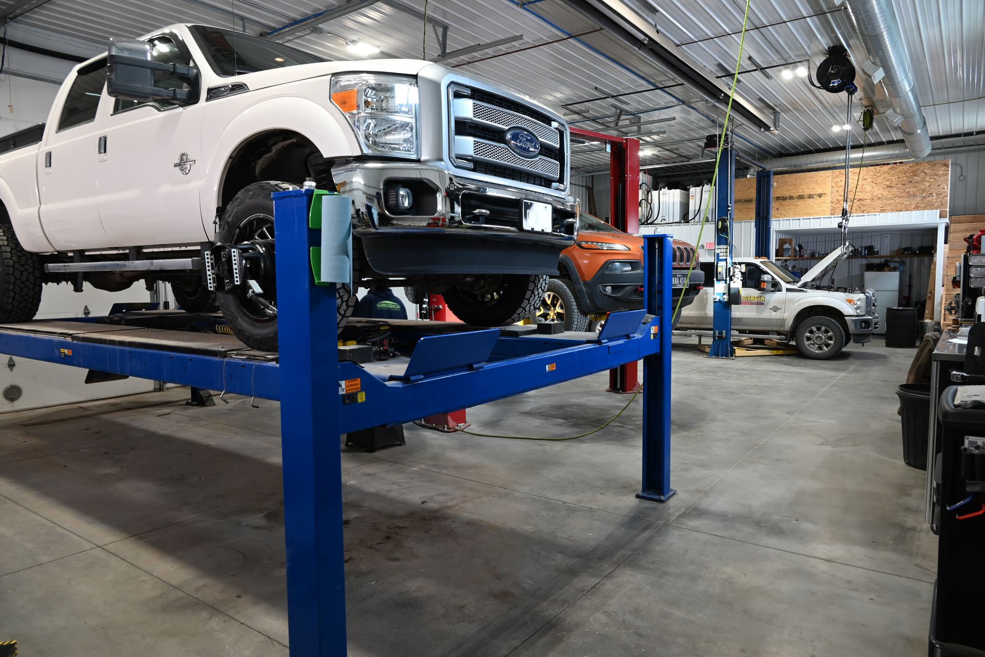 Lifted, mint green and dark green Ford pickup truck with chrome roll bar and oversized tires.