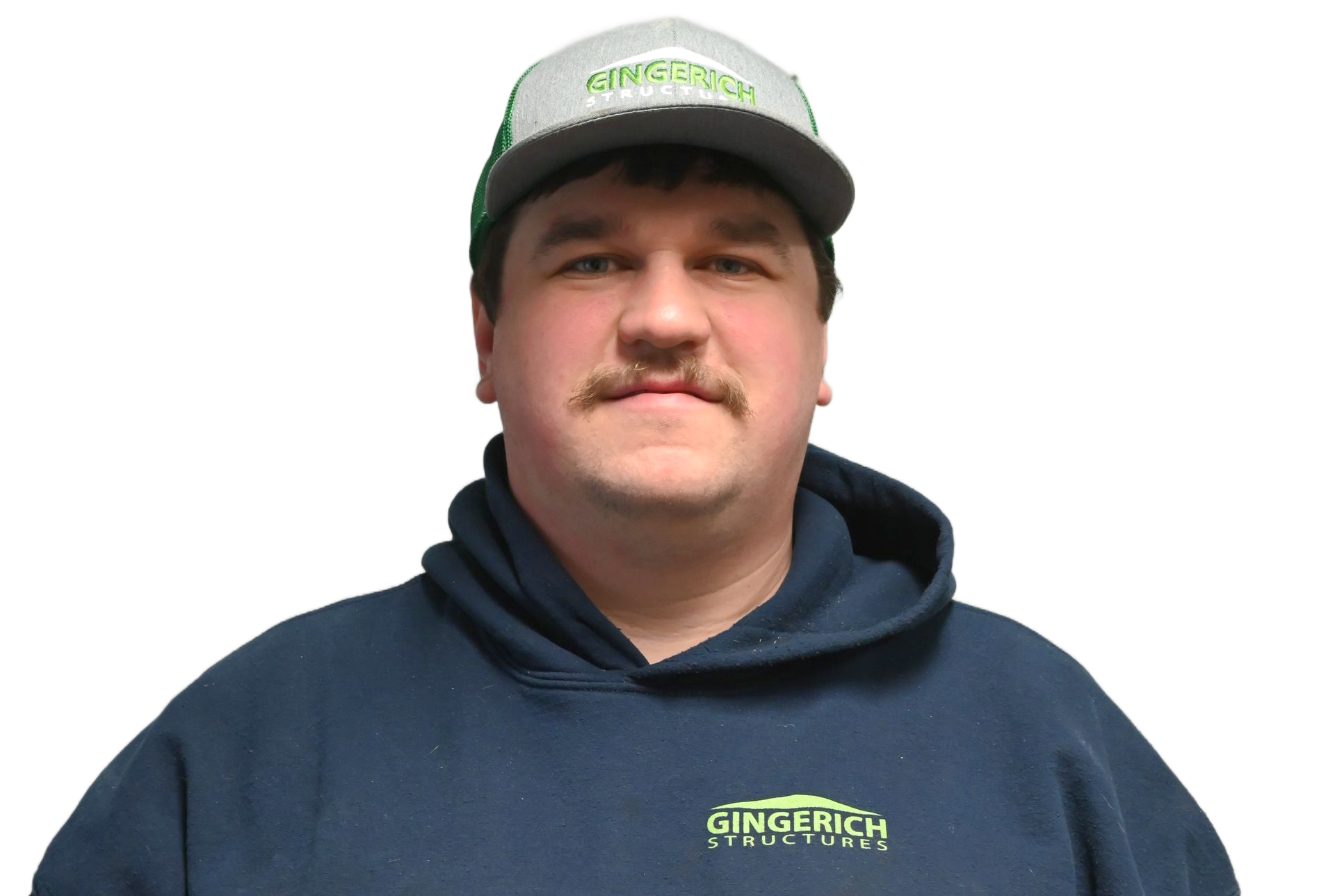 A man in a navy hoodie and cap stands in front of a white metal wall with partial signage.