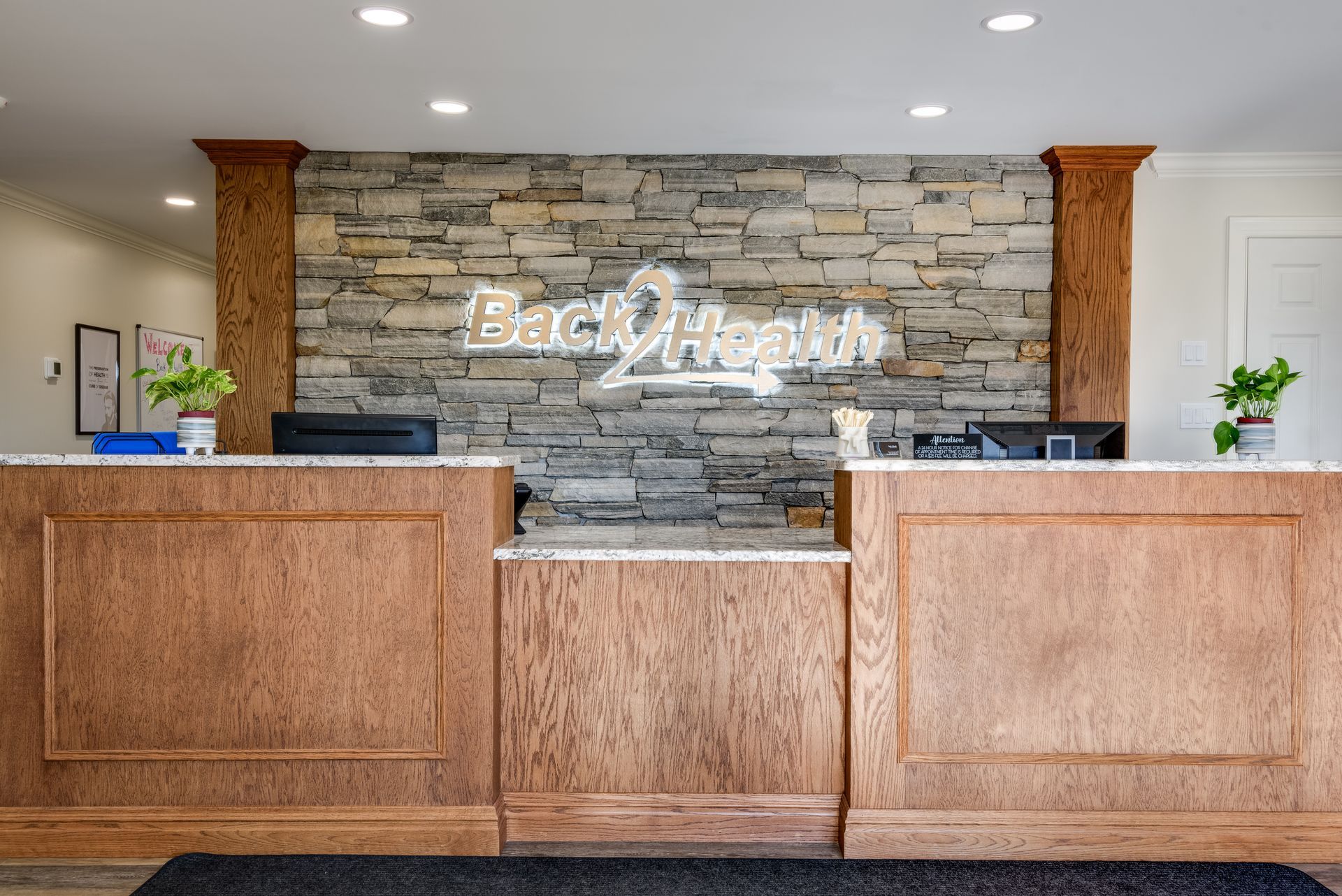 The front desk of a hotel with a stone wall behind it.