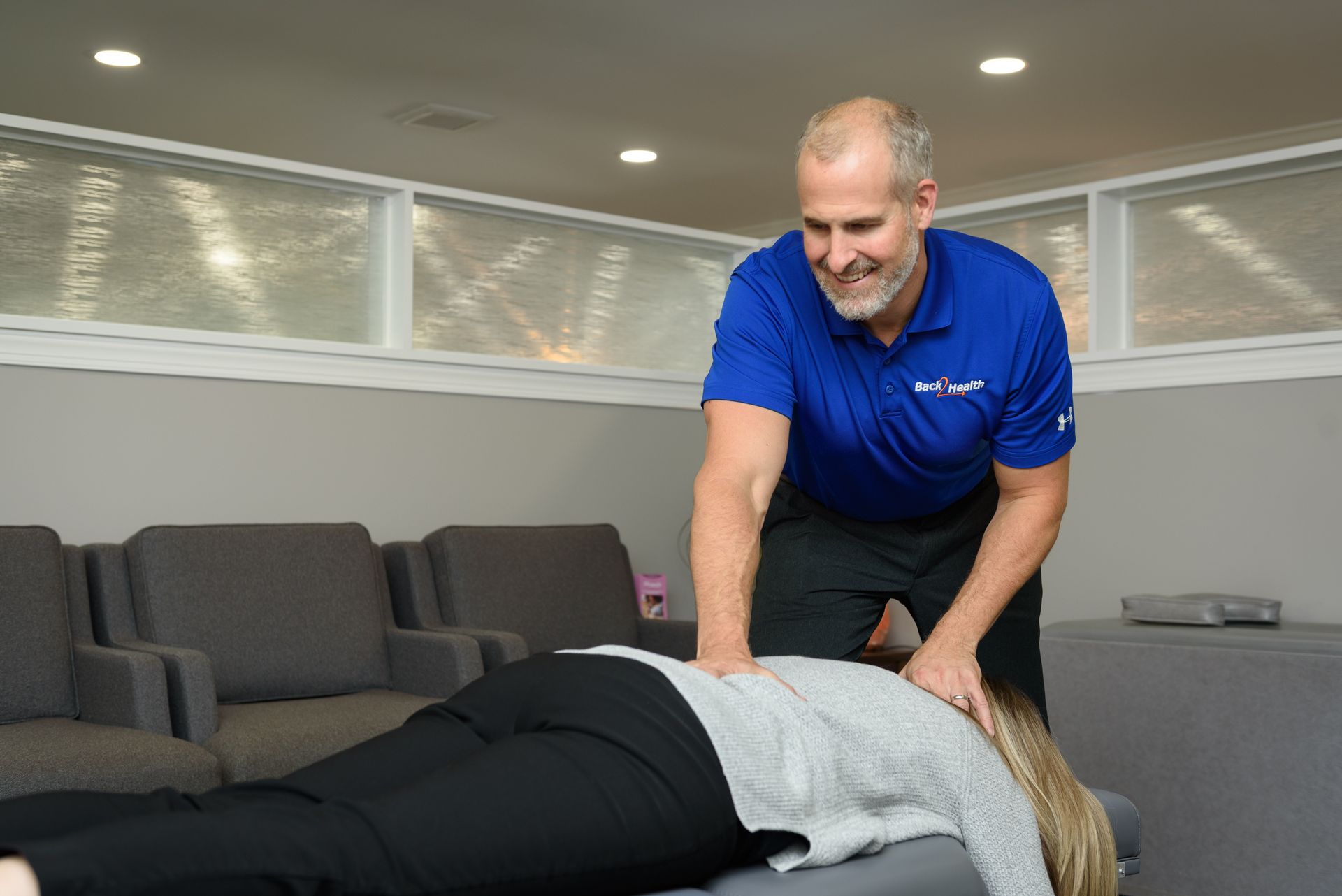 A man is giving a woman a massage in a waiting room.