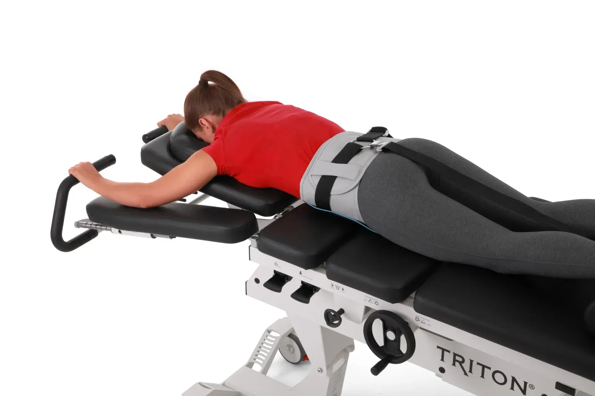 A woman is laying on a triton exercise machine.