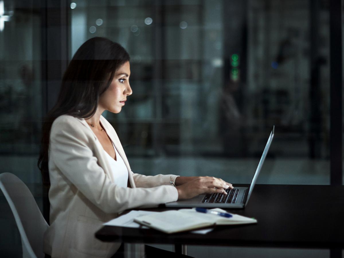 A woman is sitting at a table using a laptop computer.