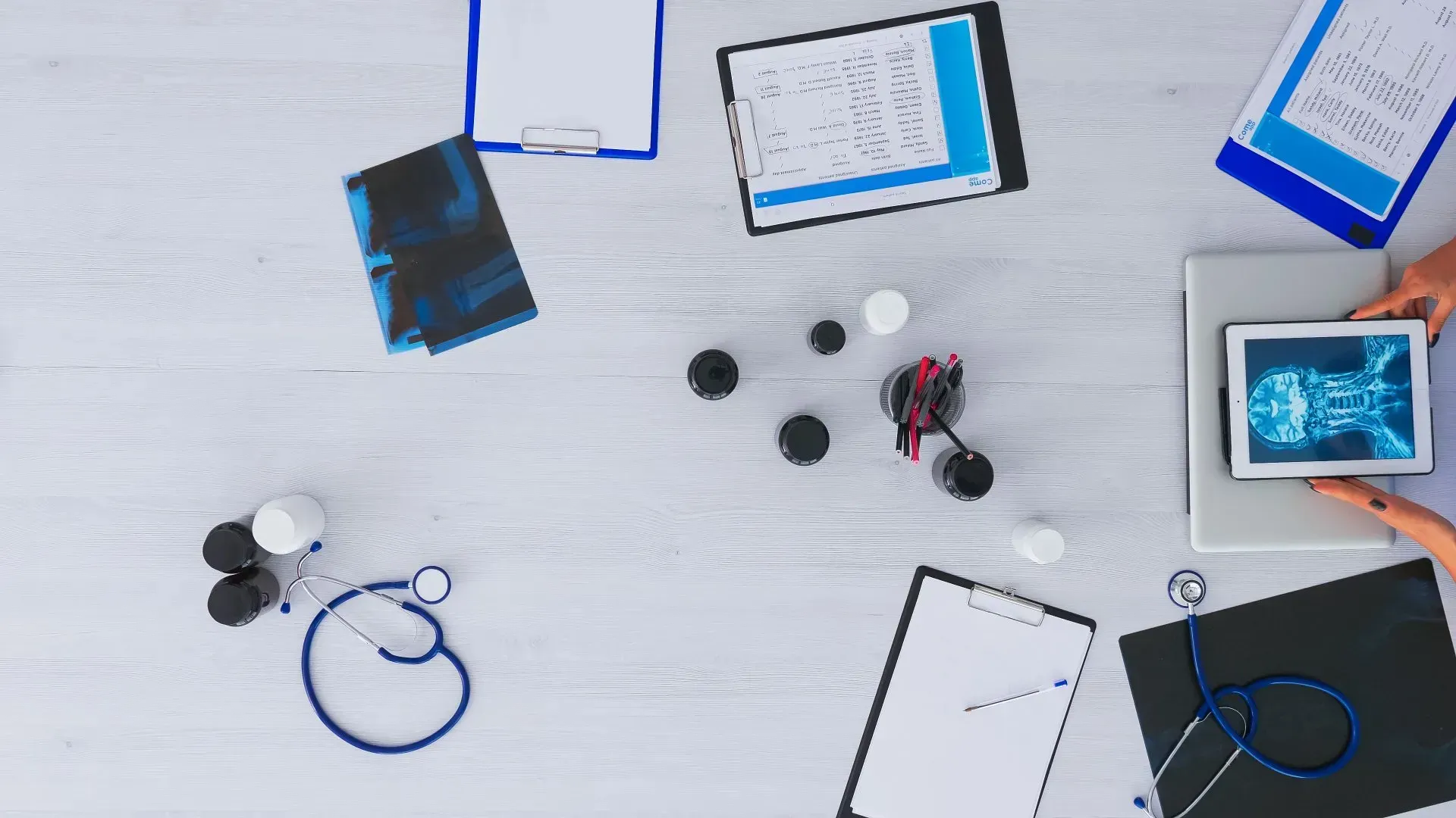 A doctor is sitting at a table with a tablet and a stethoscope.