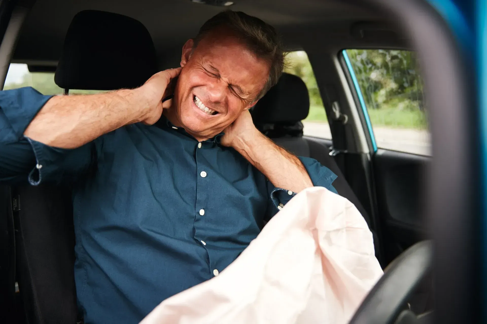 A man is sitting in the back seat of a car with his head in his hands.