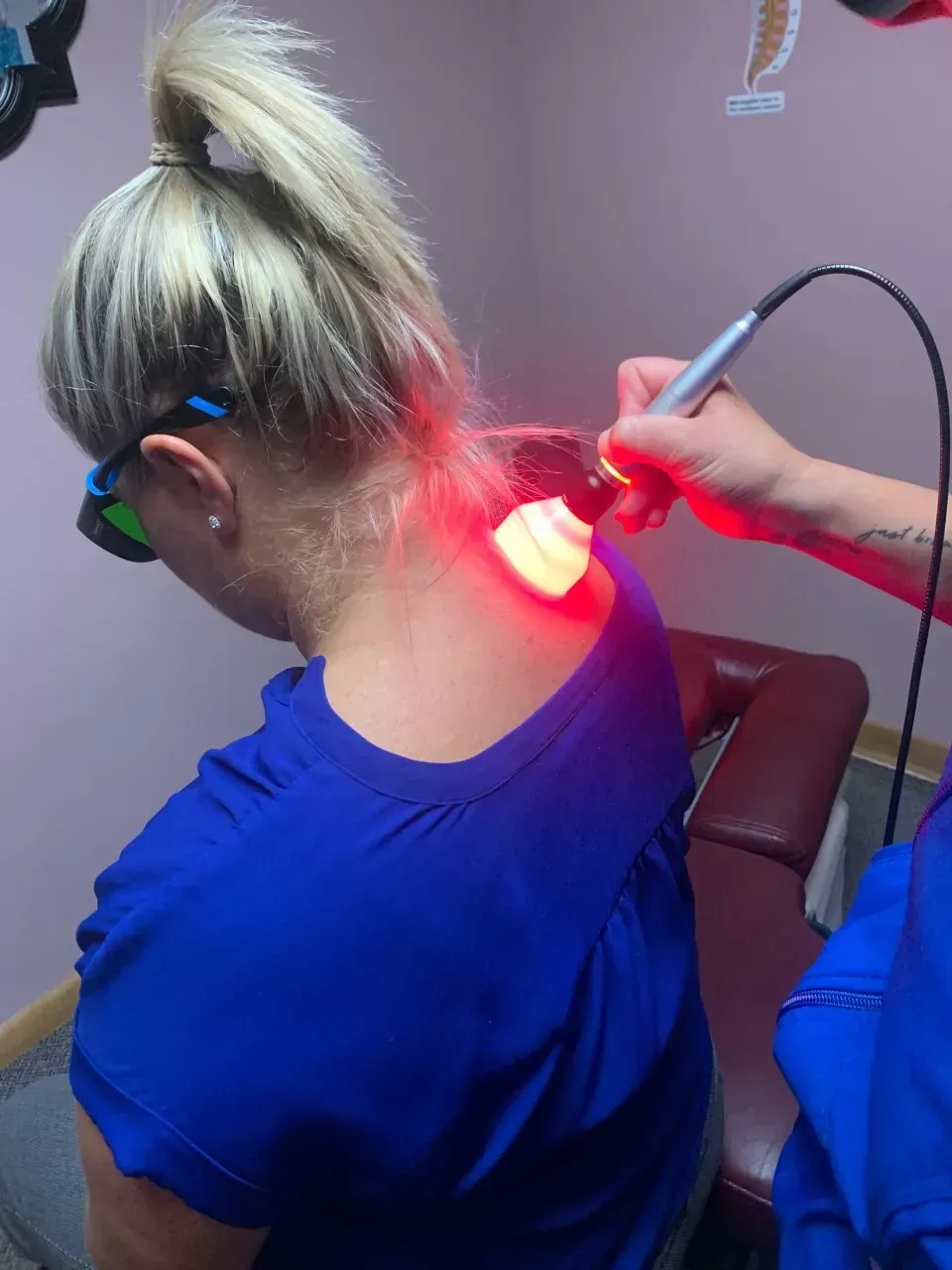 A woman in a blue shirt is getting a red light on her back