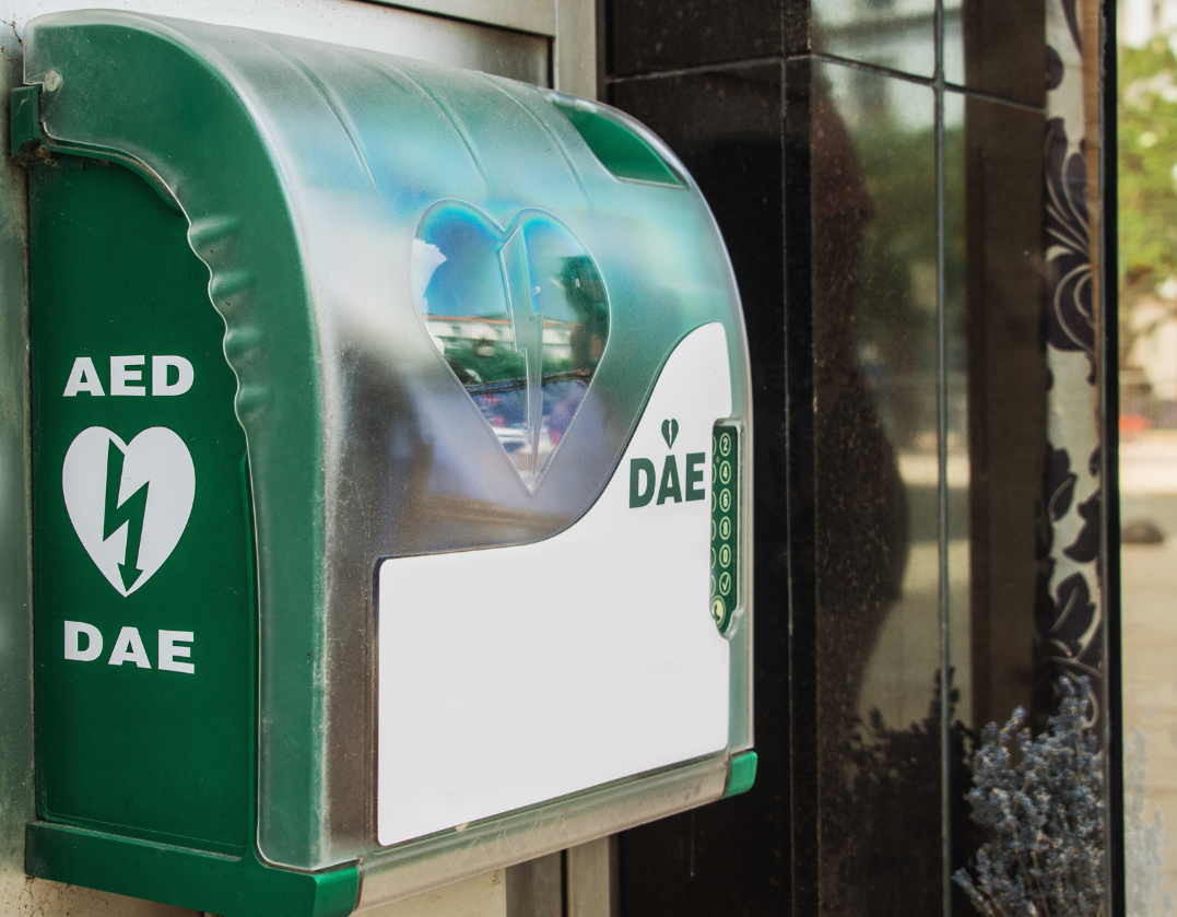 DEA vert (défibrillateur externe automatisé) monté sur un mur, avec le symbole du cœur et le mot « DEA ».