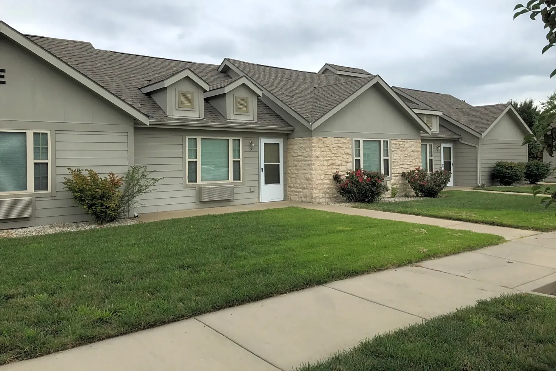 a row of Crossgate Casitas housing with a lush green lawn in front of them .