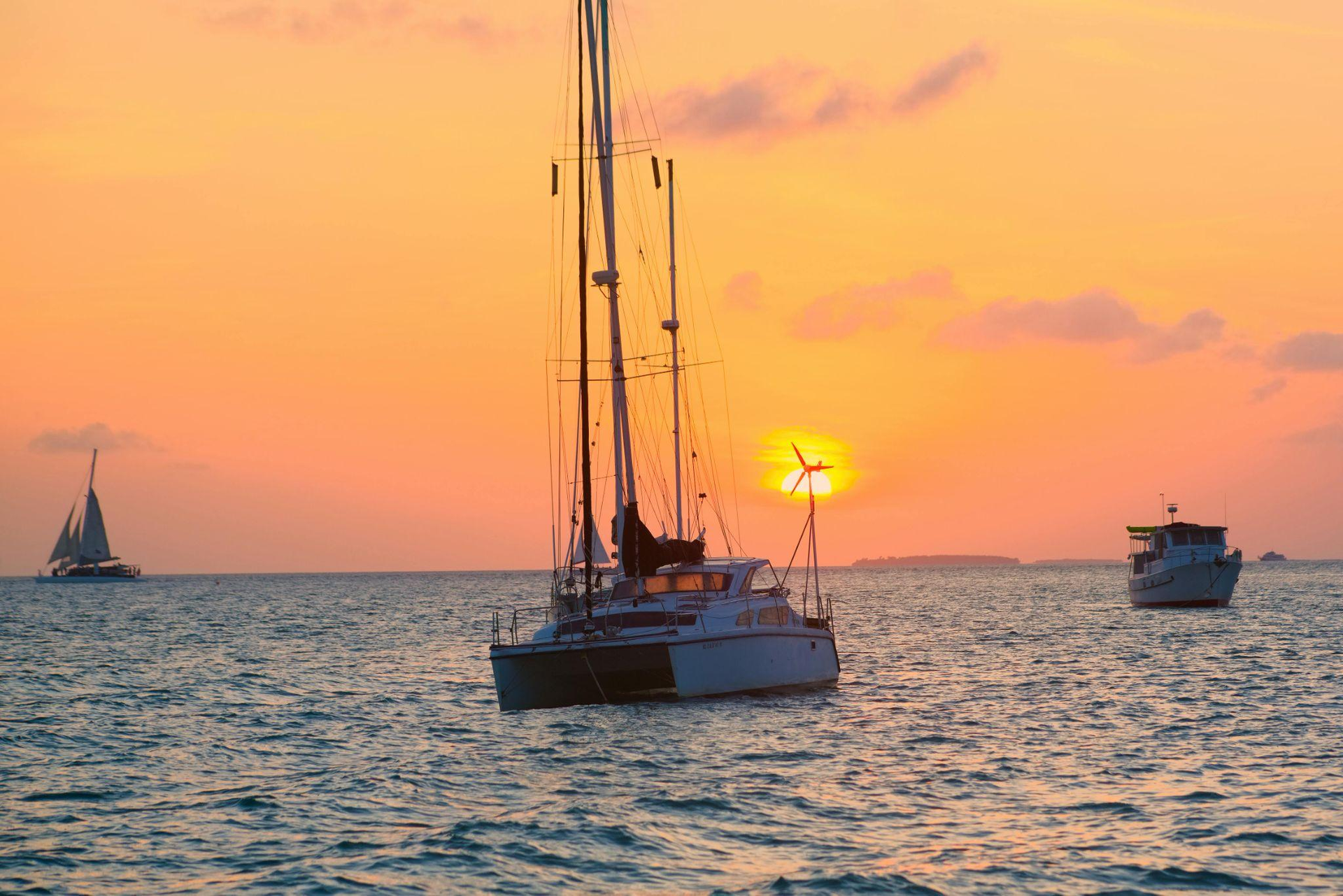 a sailboat in the ocean during sunset