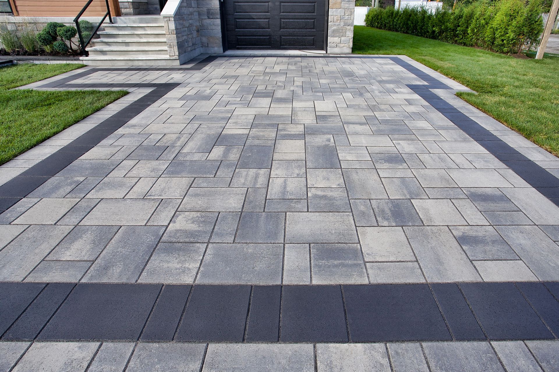 A brick paved driveway with a black border is leading to a house in Essex.