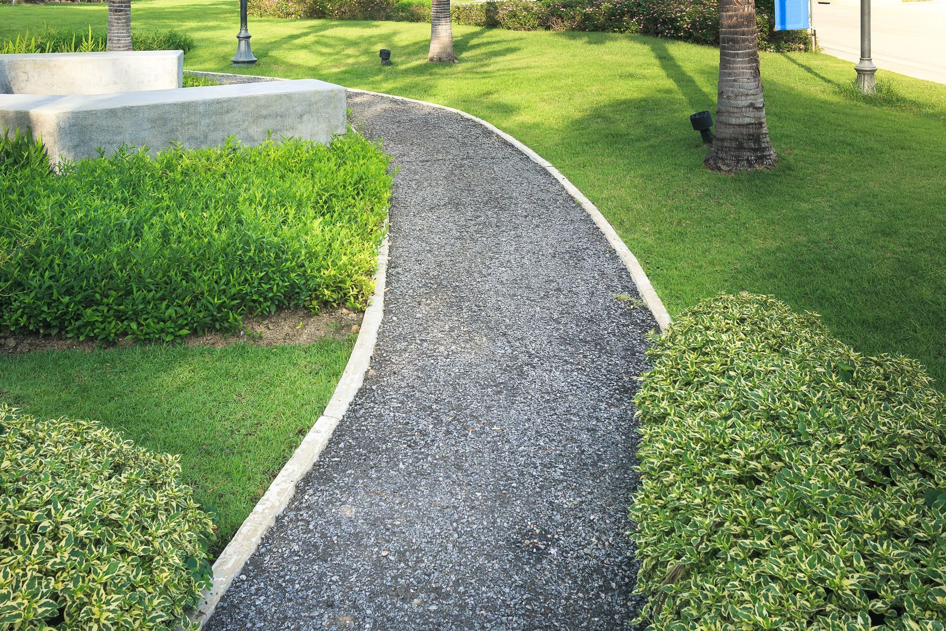 A resin path in a park in Essex surrounded by grass and bushes. Installed by Essex Resin Driveways