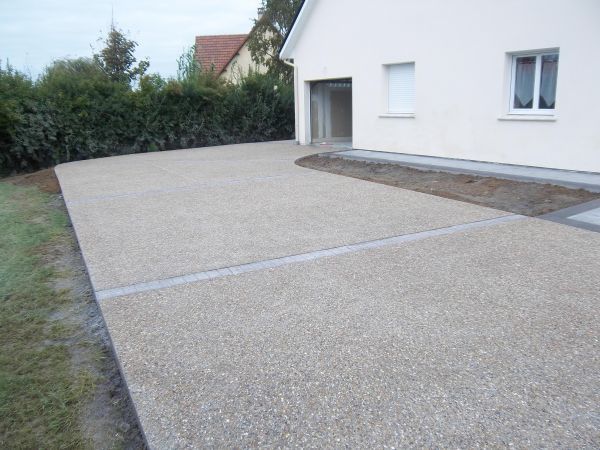 A concrete driveway in Chelmsford, Essex leading to a white house. Installed by Essex Resin driveways