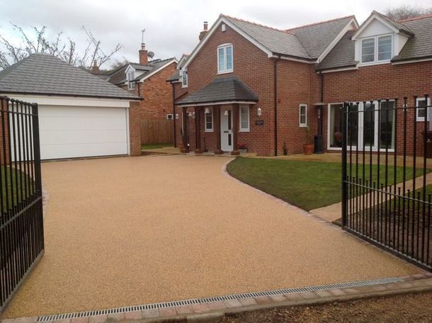 A large brick house in Essex with a resin driveway leading to it and a garage. Installed by Essex Resin driveways