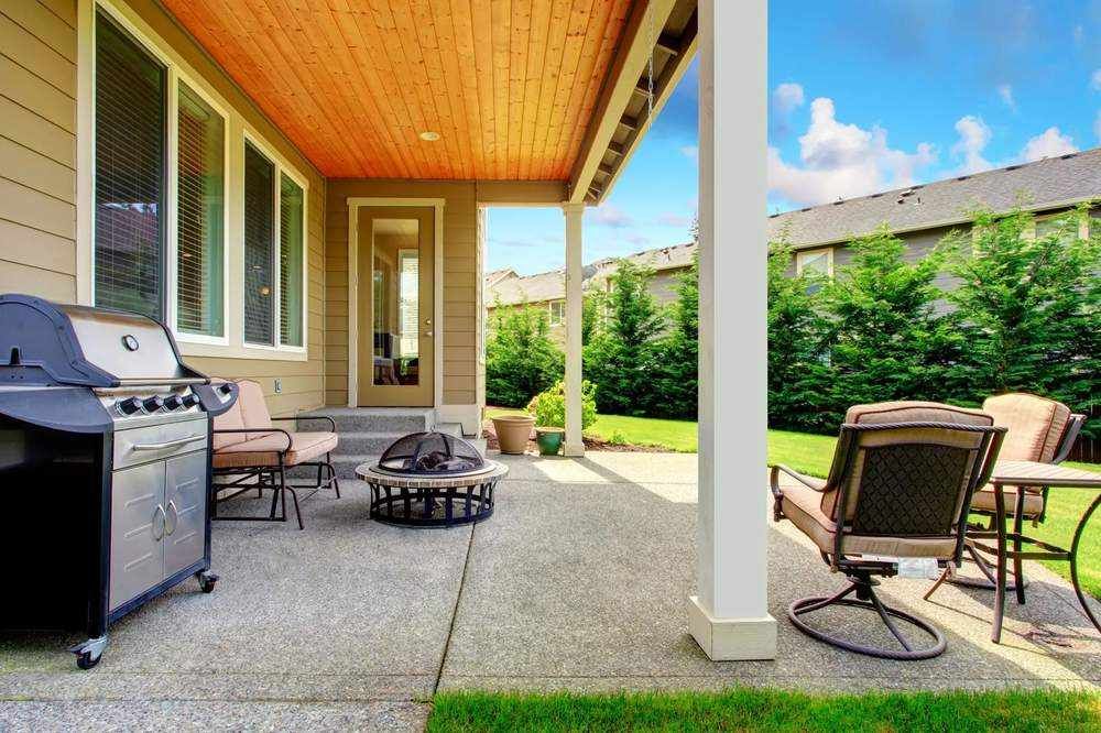A resin bound patio with a grill , chairs , tables and a fire pit in Essex.