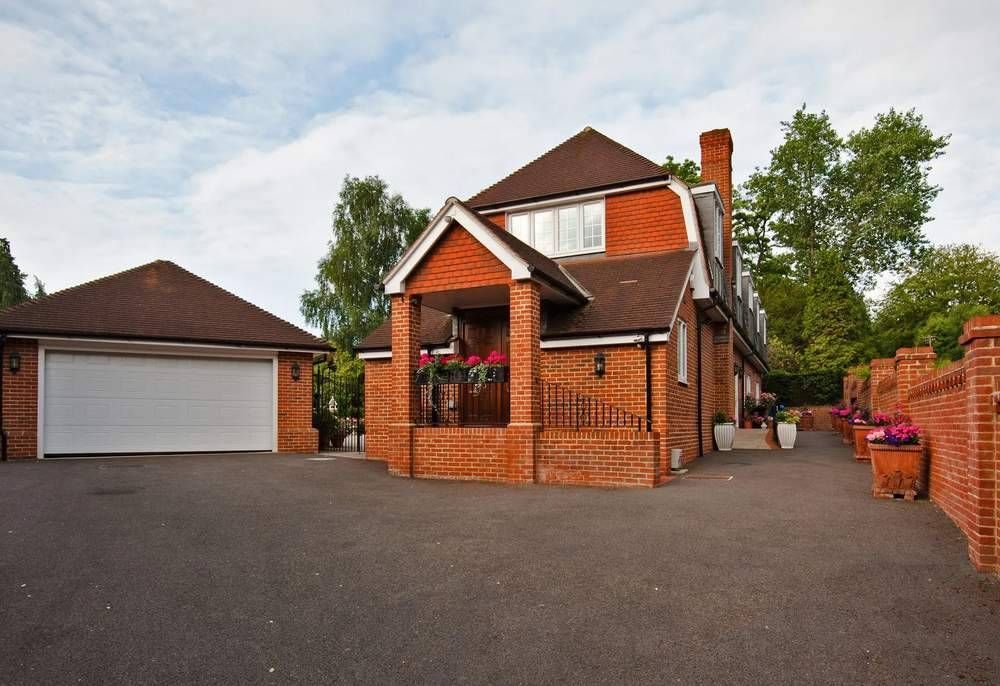 A large brick house in Essex with a white garage door and a resin bound driveway installed by Essex Resin driveways