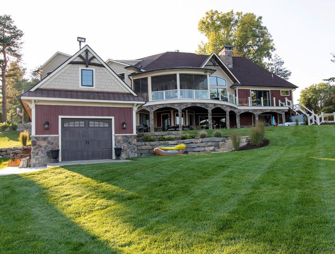 Luxurious home with attached garage, landscaped lawn, and a lake view.