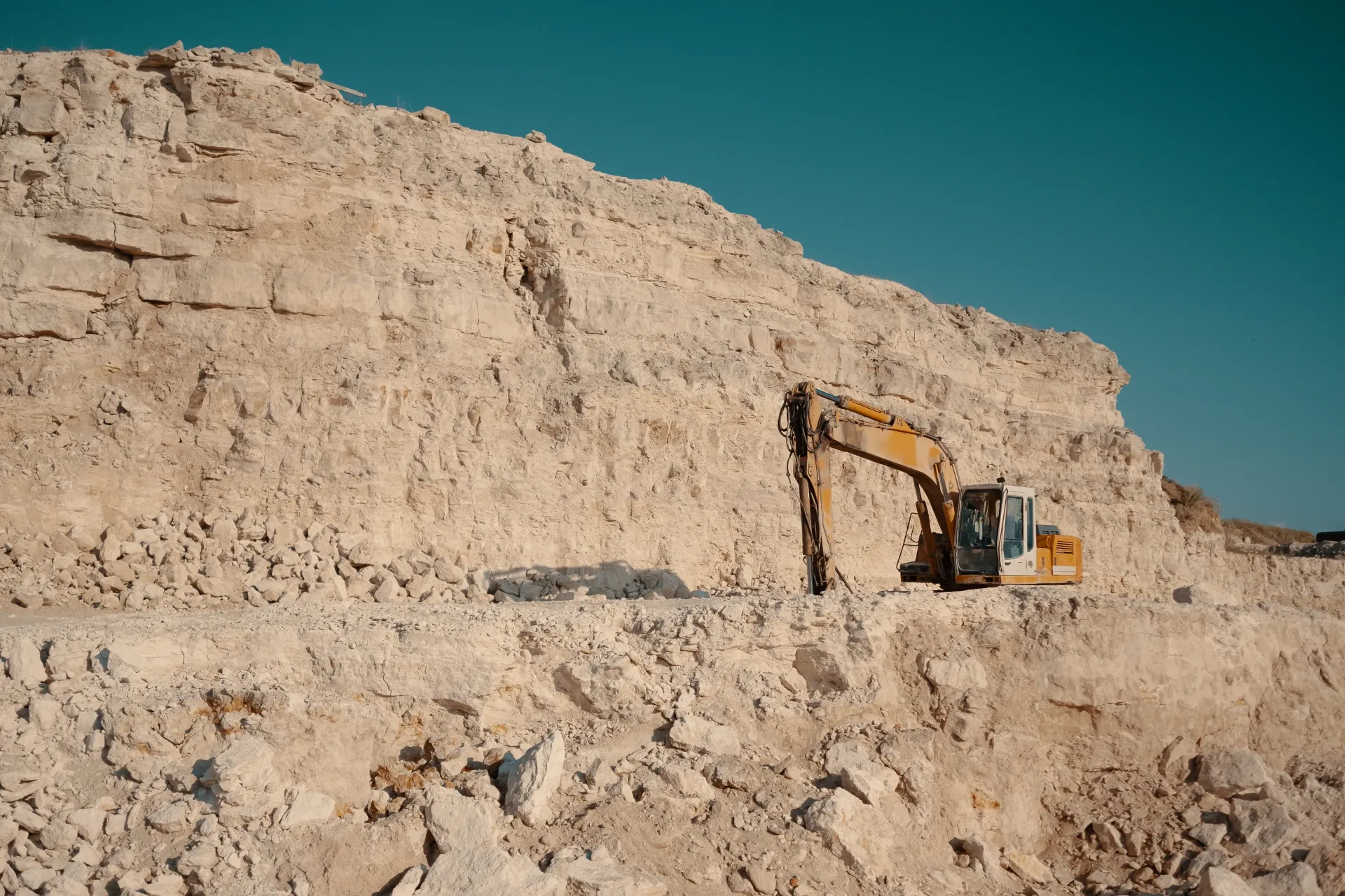 A large excavator working in a quarry, extracting and breaking down stone and crusher run materials.