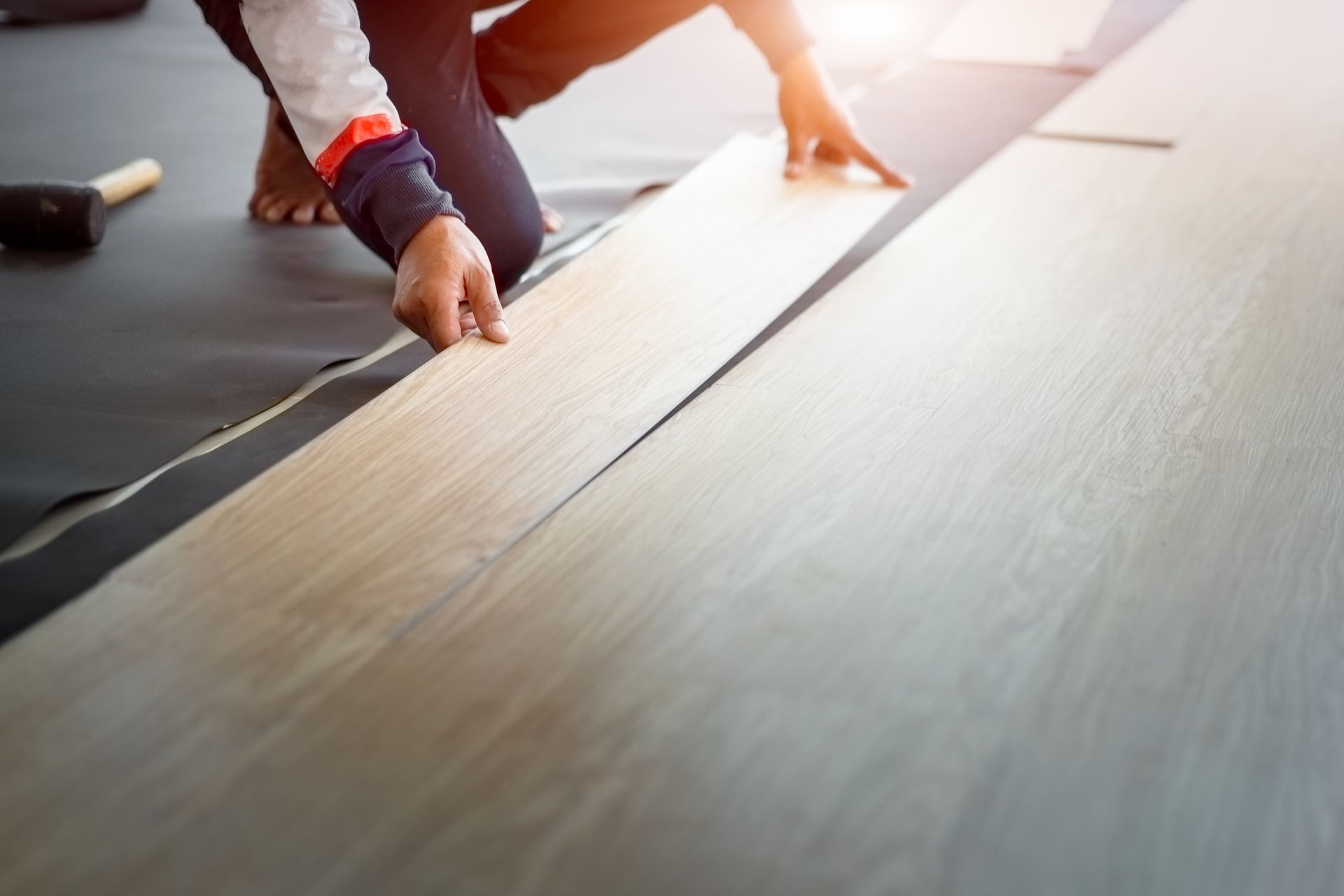 A person is installing a wooden floor in a room.