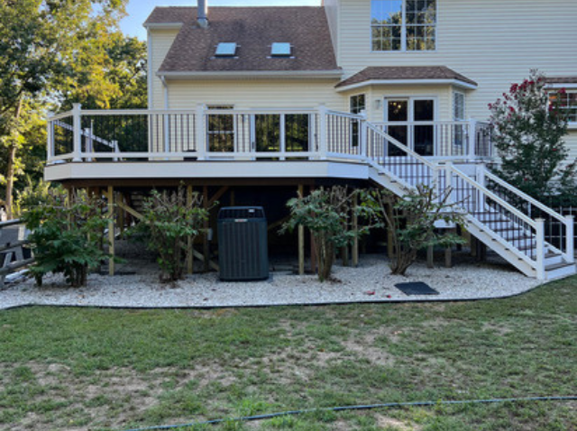 A large white house with a large deck and stairs.