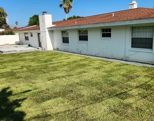 White house with red roof, chimney, and windows; a green lawn.