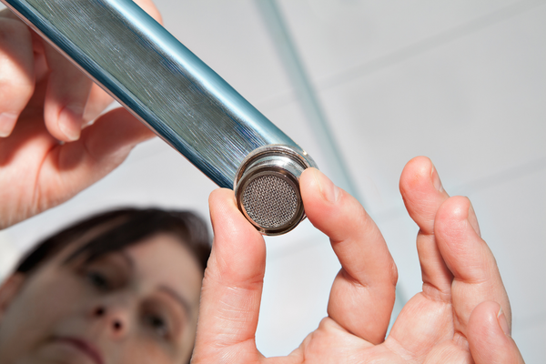 A woman adding Faucet aerator on kitchen faucet