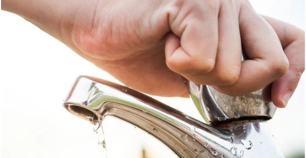 a hand turning off a faucet
