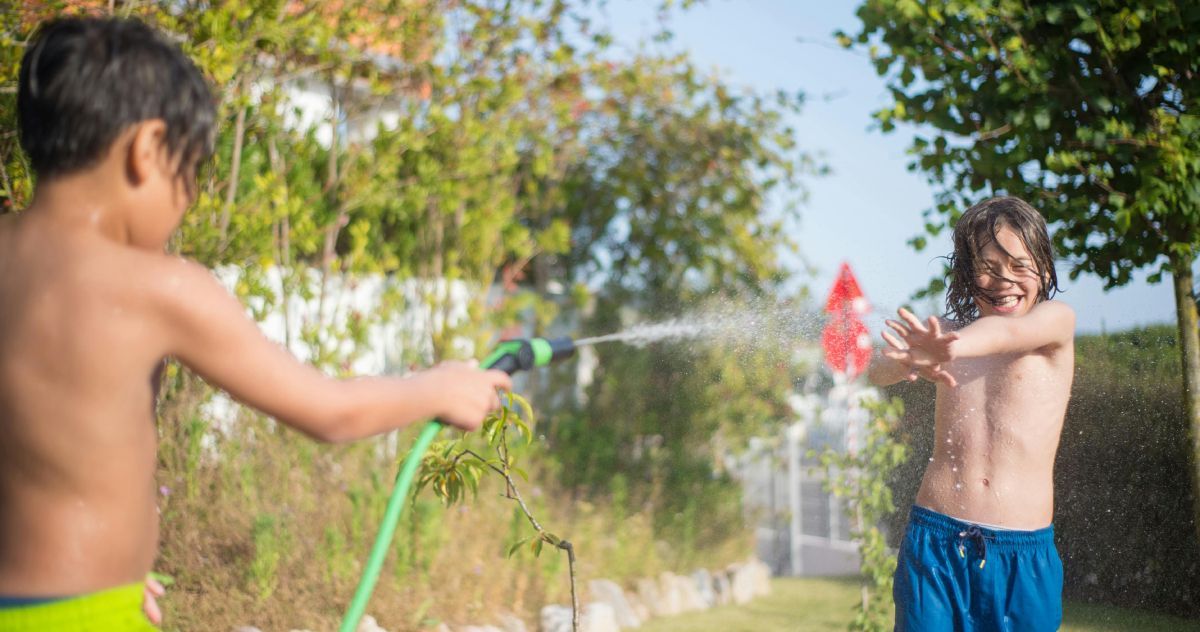 boys playing with garden sprinkler