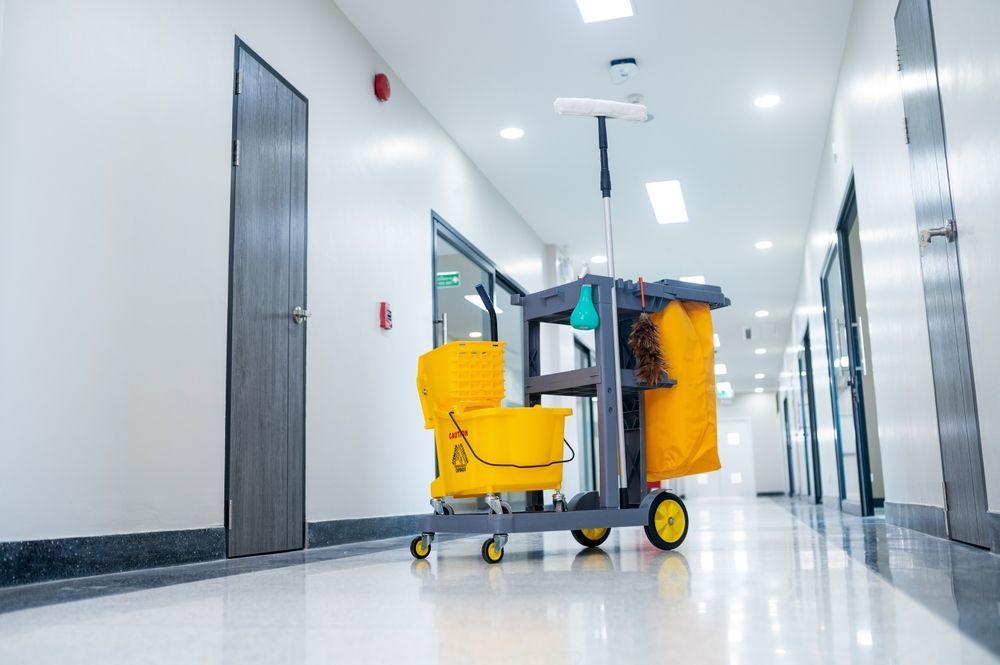 A cleaning cart is parked in a hallway of a building.
