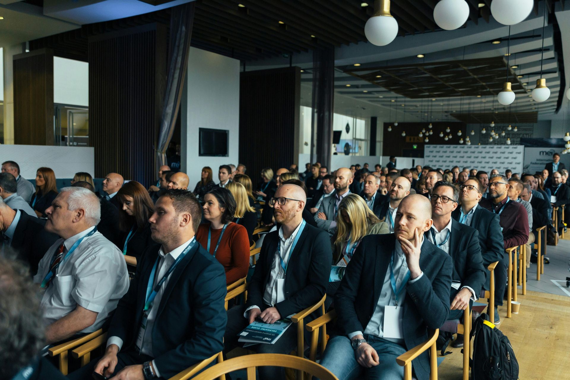A large group of people are sitting in chairs at a conference.