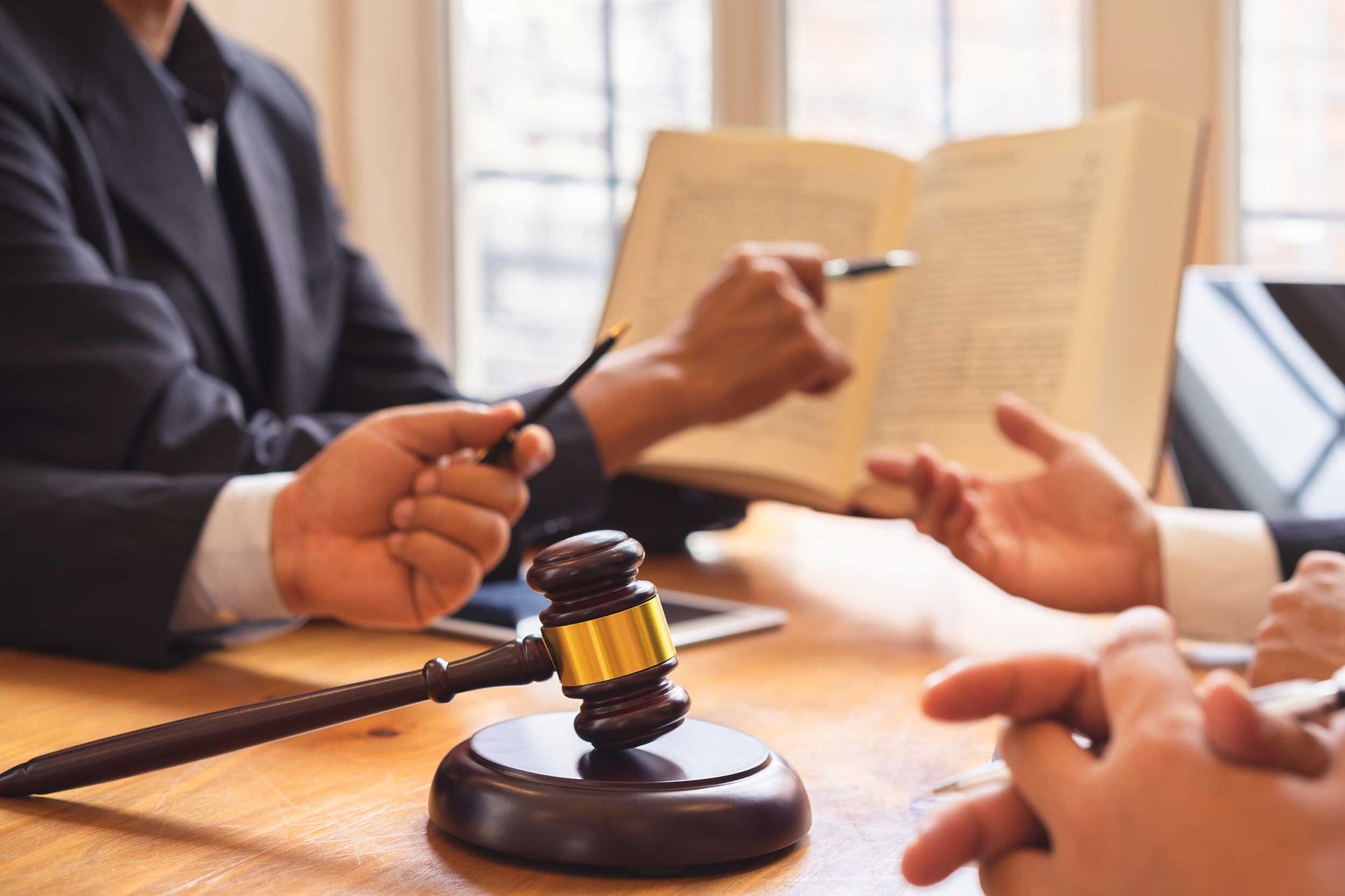 Lawyer reviewing contract with client, legal gavel on desk, consultation in law office meeting room.