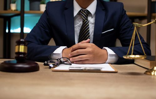 A man in a suit and tie is sitting at a desk with a judge 's gavel and scales of justice.