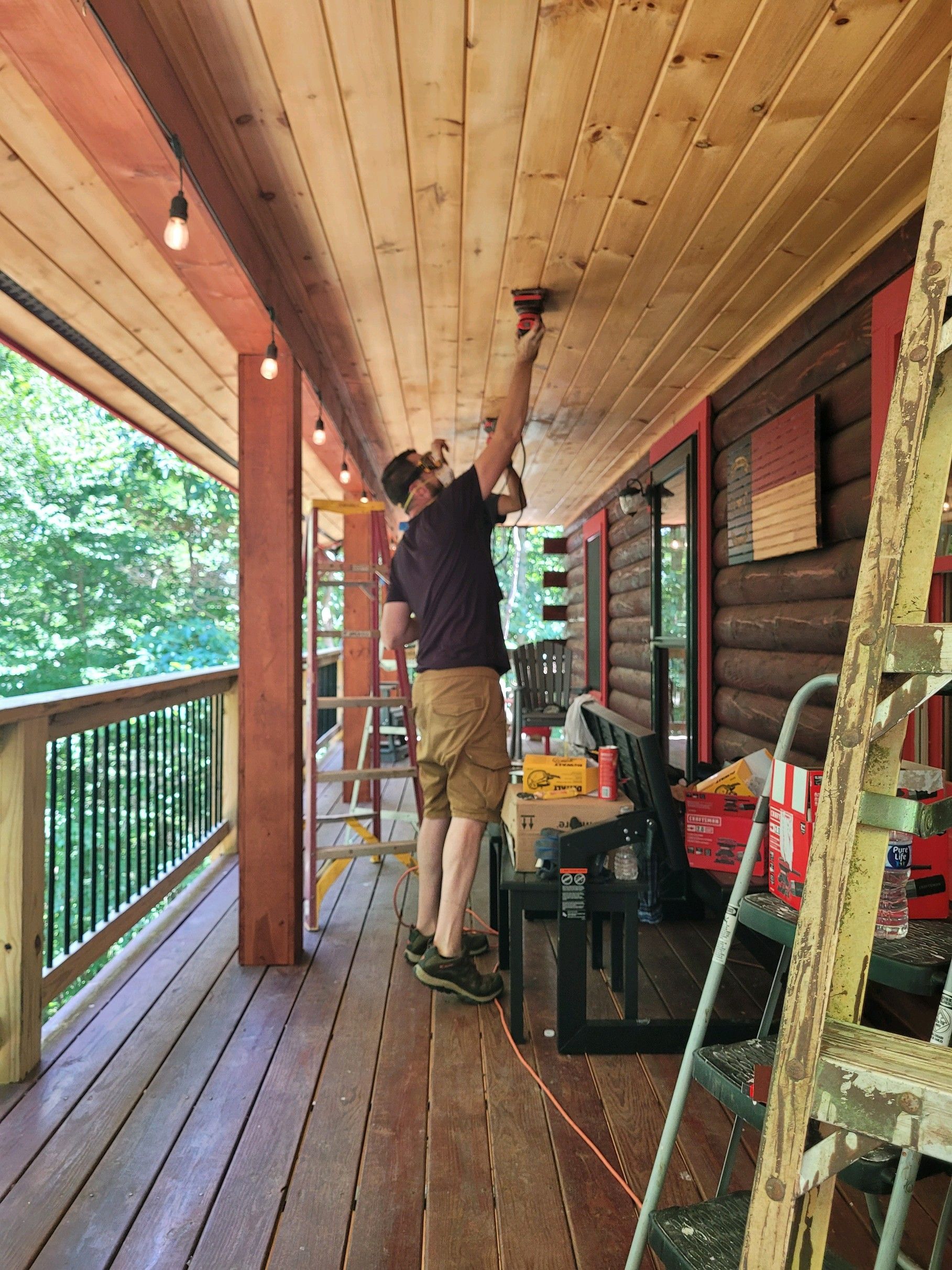 A man is working on the ceiling of a porch.