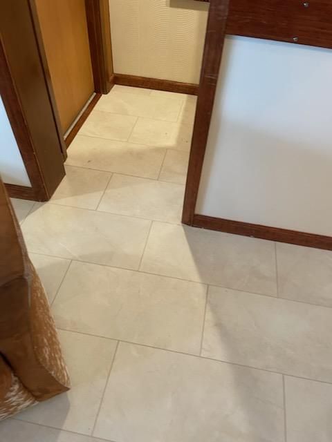 A white tile floor with a wooden trim in a room.