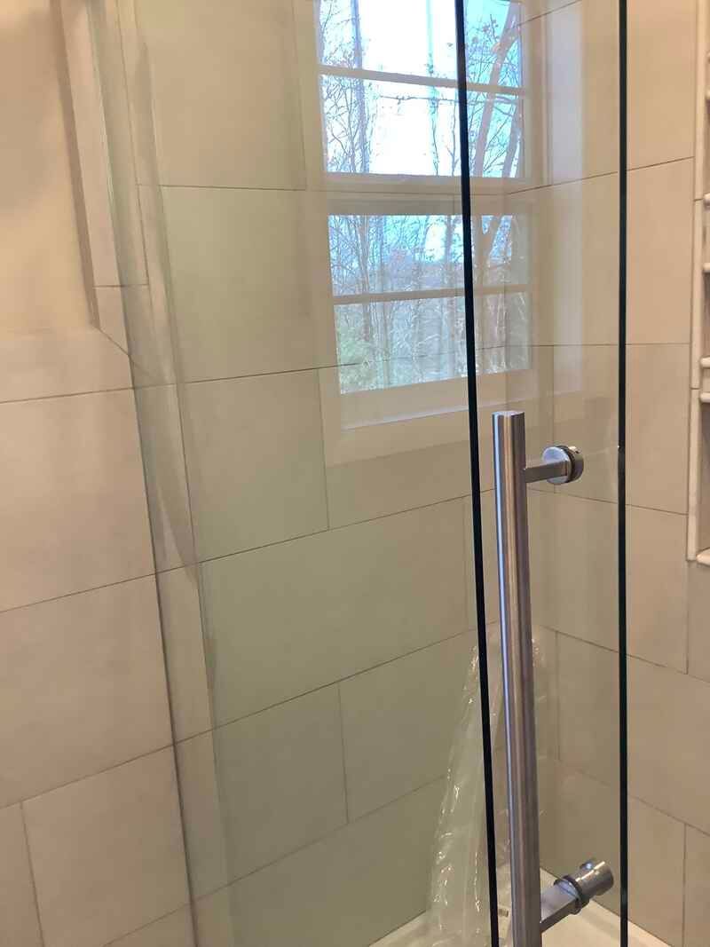 A bathroom with a sliding glass shower door and a window.